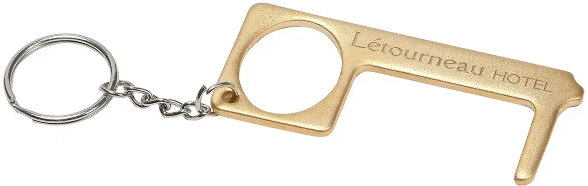 Custom brass no-touch tool in use pressing a keypad, logo-ready handle