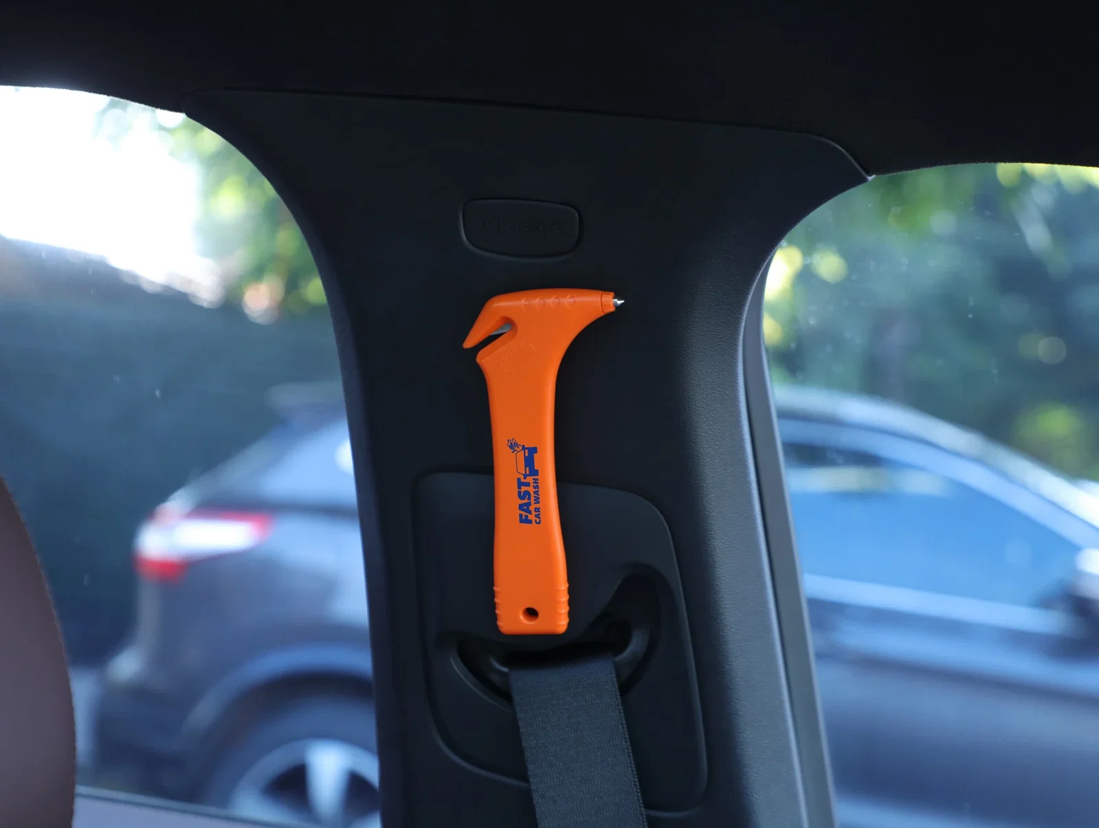 Car Escape Tool with Cutter shown mounted for quick reach inside a vehicle, in use