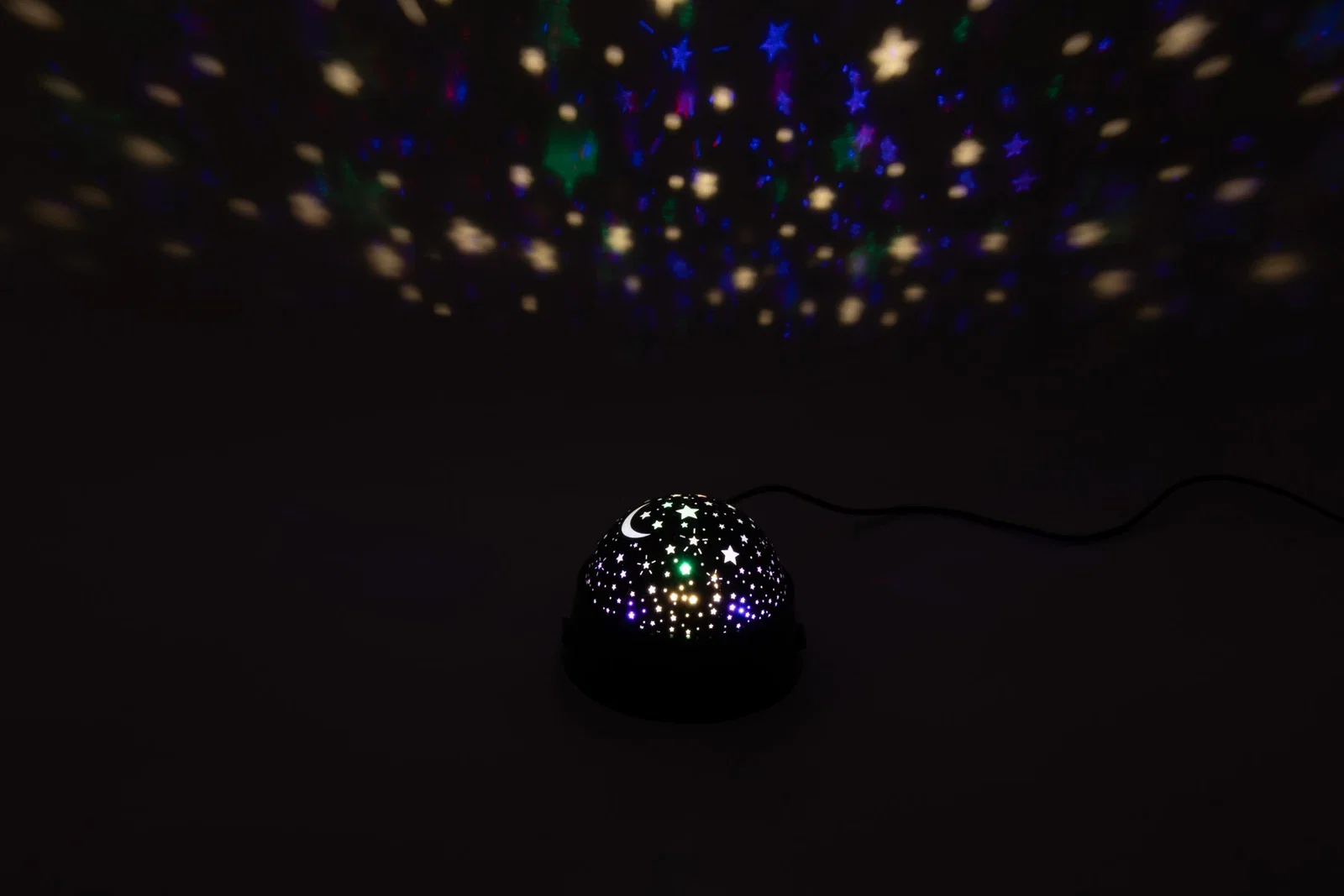 Constellation Night Light projecting stars onto a bedroom ceiling, branded night light in use