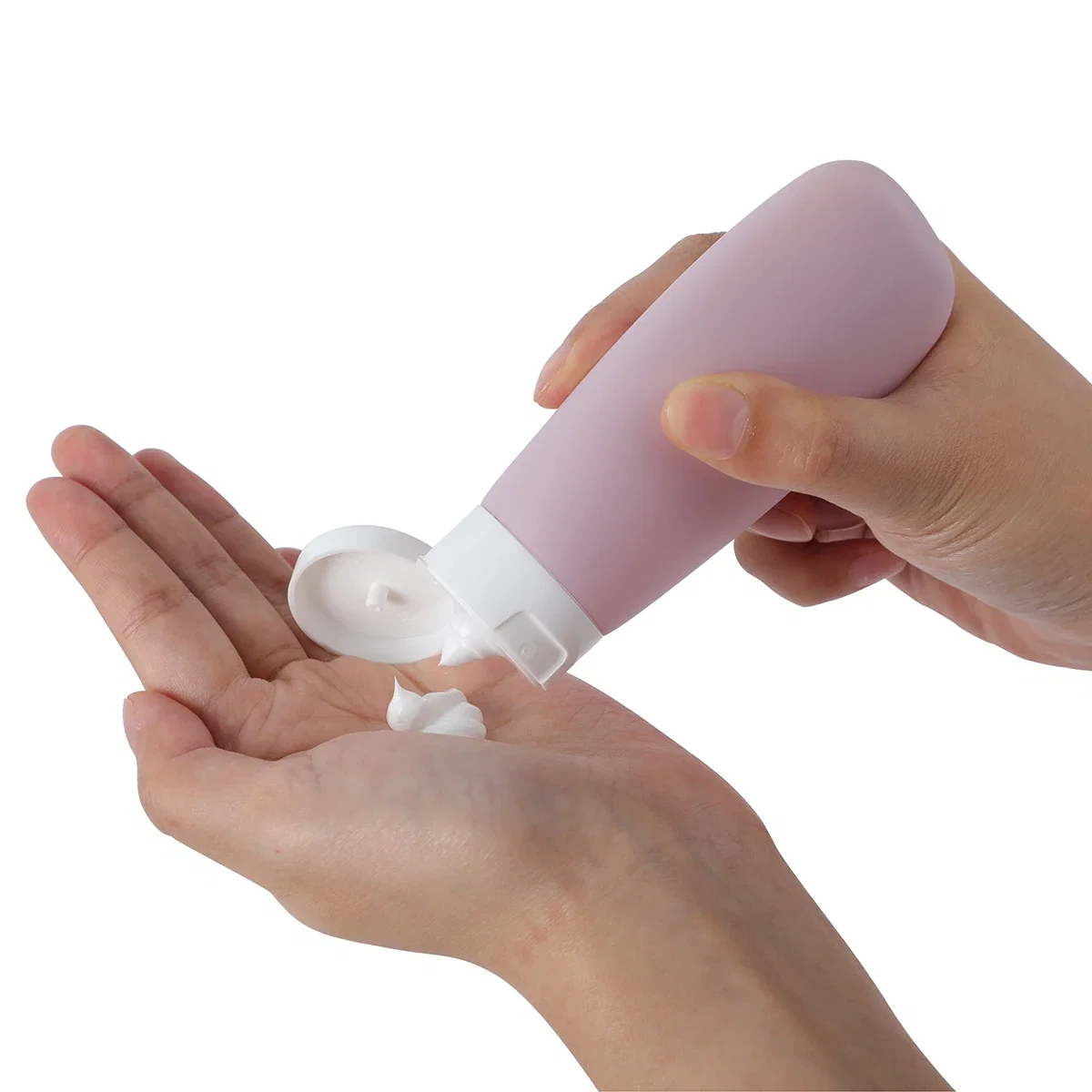 Continental travel bottle in blush pink dispensing lotion into a hand, in-use shot