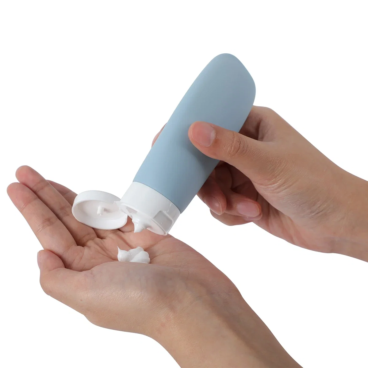 Continental travel bottle in dusty blue dispensing lotion into a hand, in-use shot
