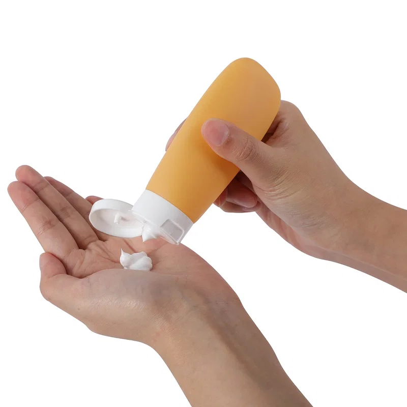 Continental travel bottle in mustard yellow dispensing lotion into a hand, in-use shot