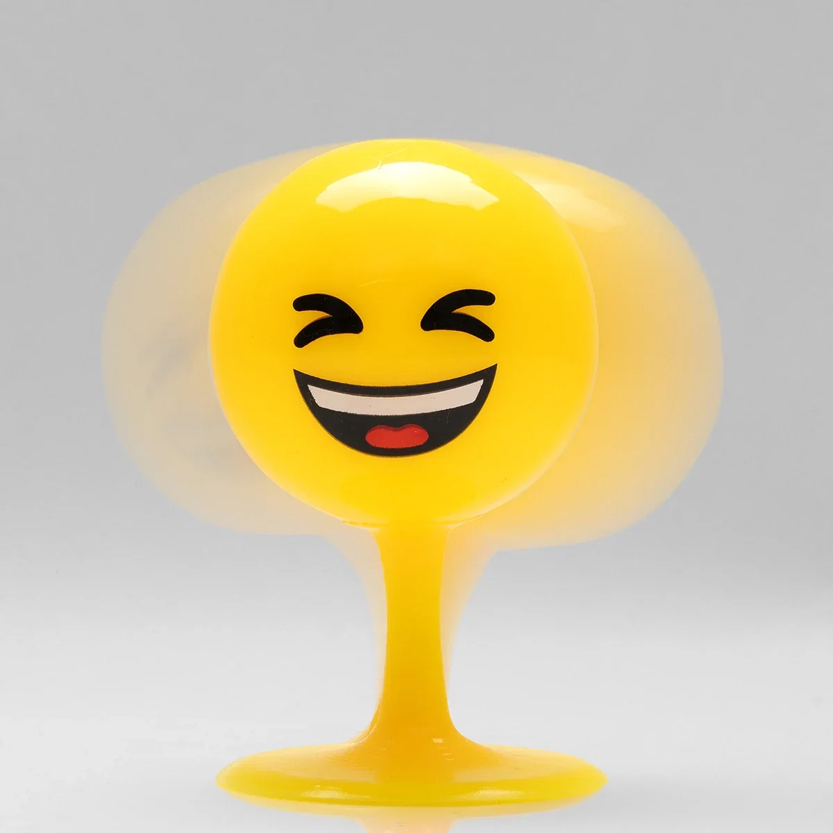 Close-up of the Emoji Bopper Desk Ball's laughing face design wobbling on its stem