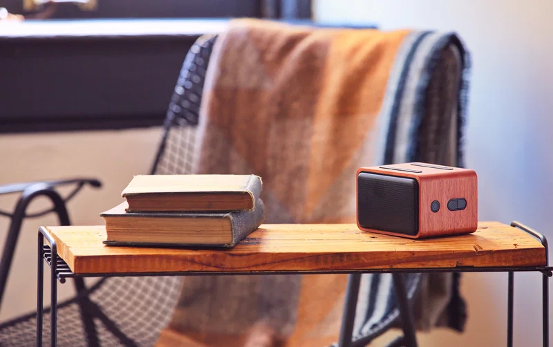 Mahogany Wireless Speaker in use, promotional speaker charging a smartphone