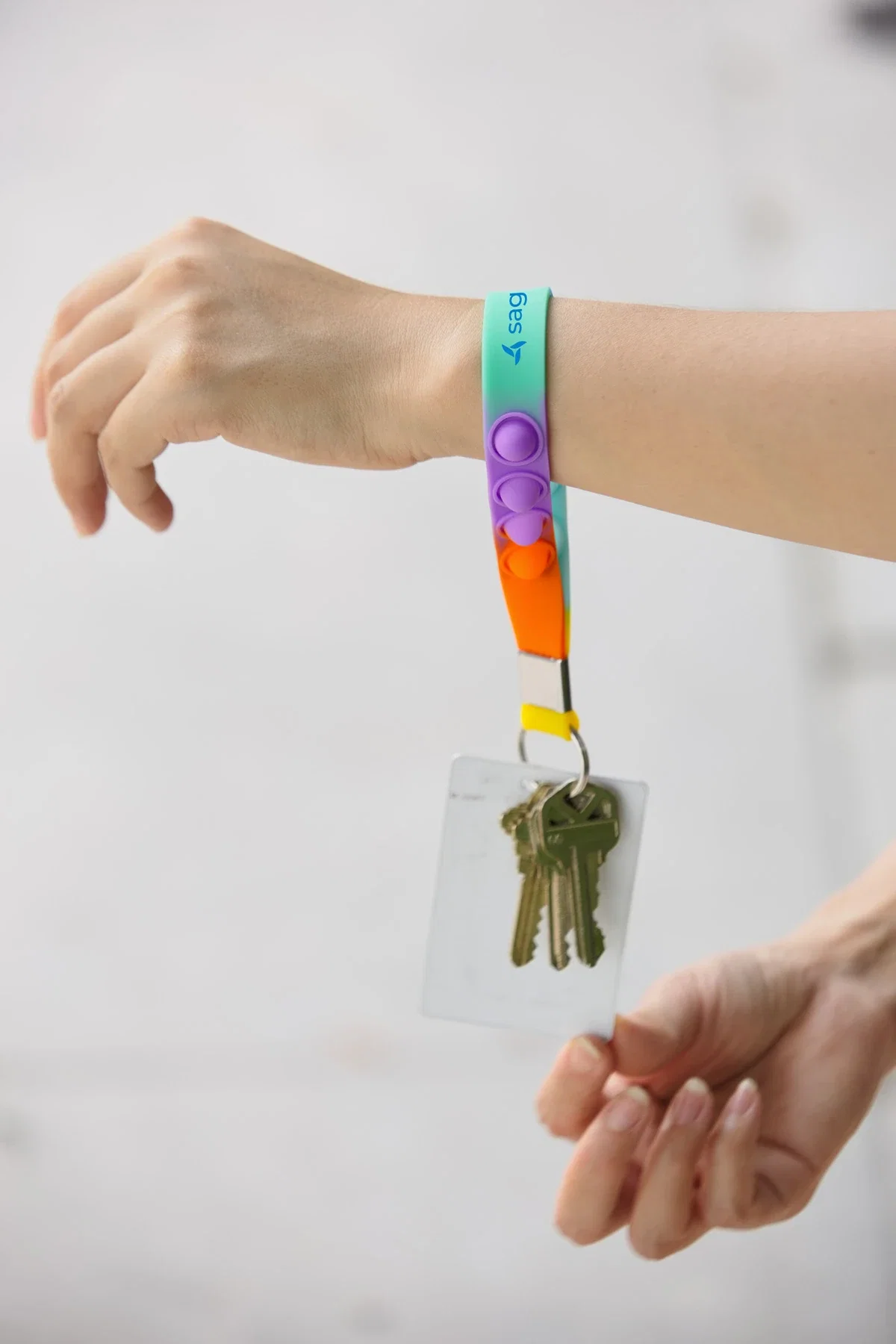 Push Pop Stress Reliever Keychain worn around the wrist with keys and an ID card attached
