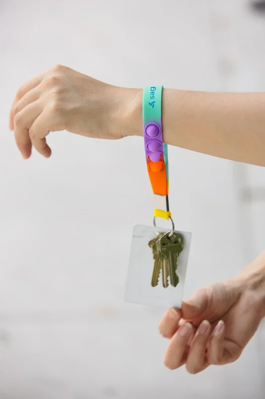 Push Pop Stress Reliever Keychain worn around the wrist with keys and an ID card attached